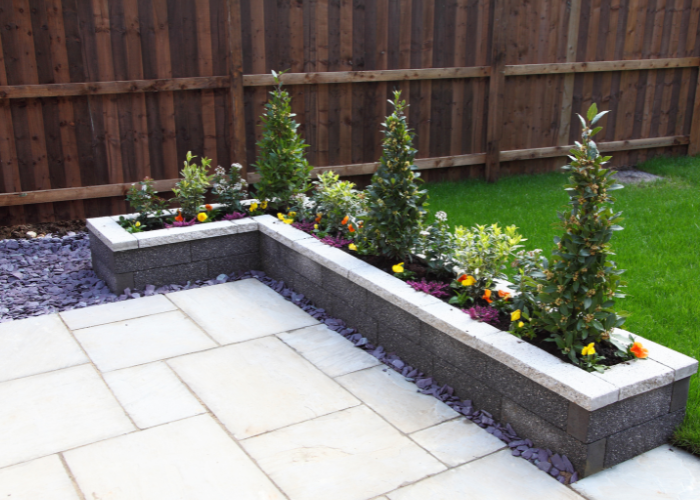 A raised patio area with a tiled corner flowerbed that curves around one corner.
